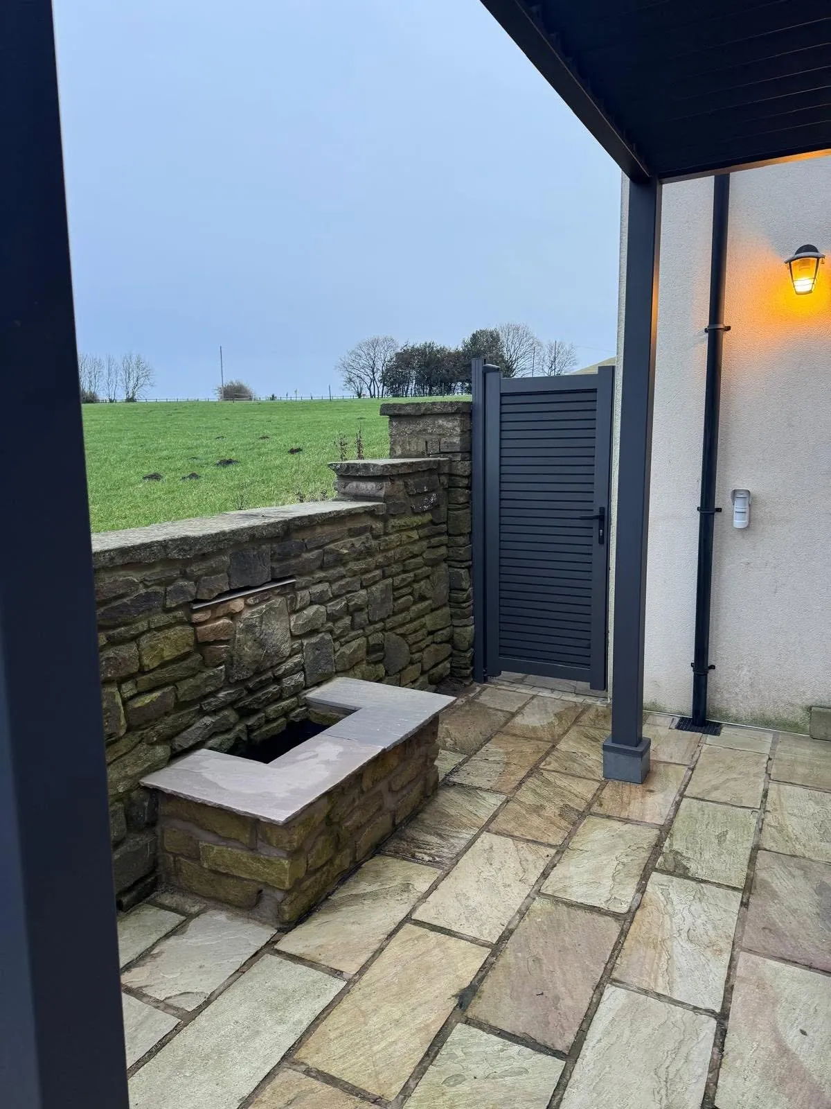 Stone-clad water feature on a sandstone patio