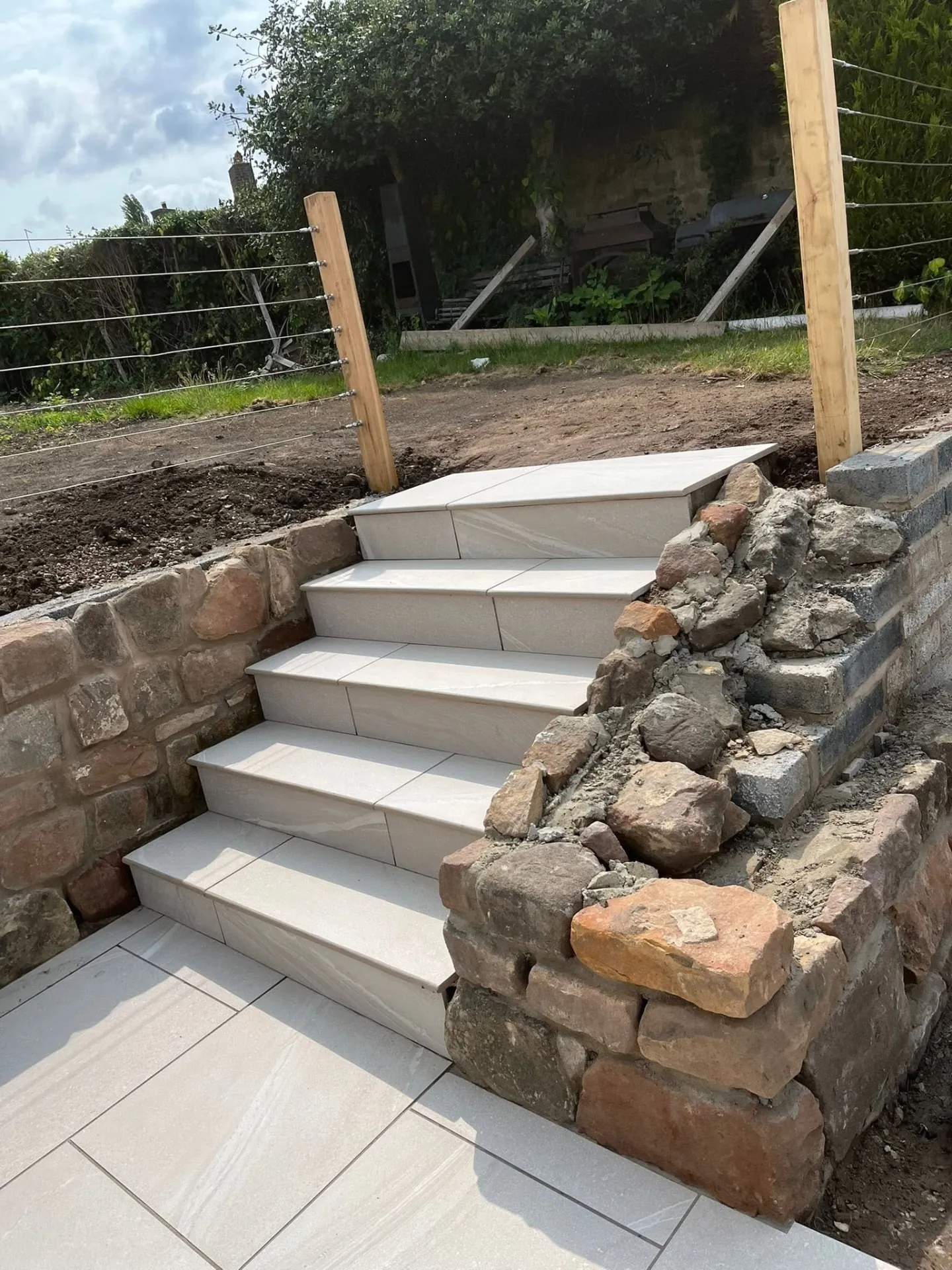 Porcelain steps under construction beside a dry stone wall