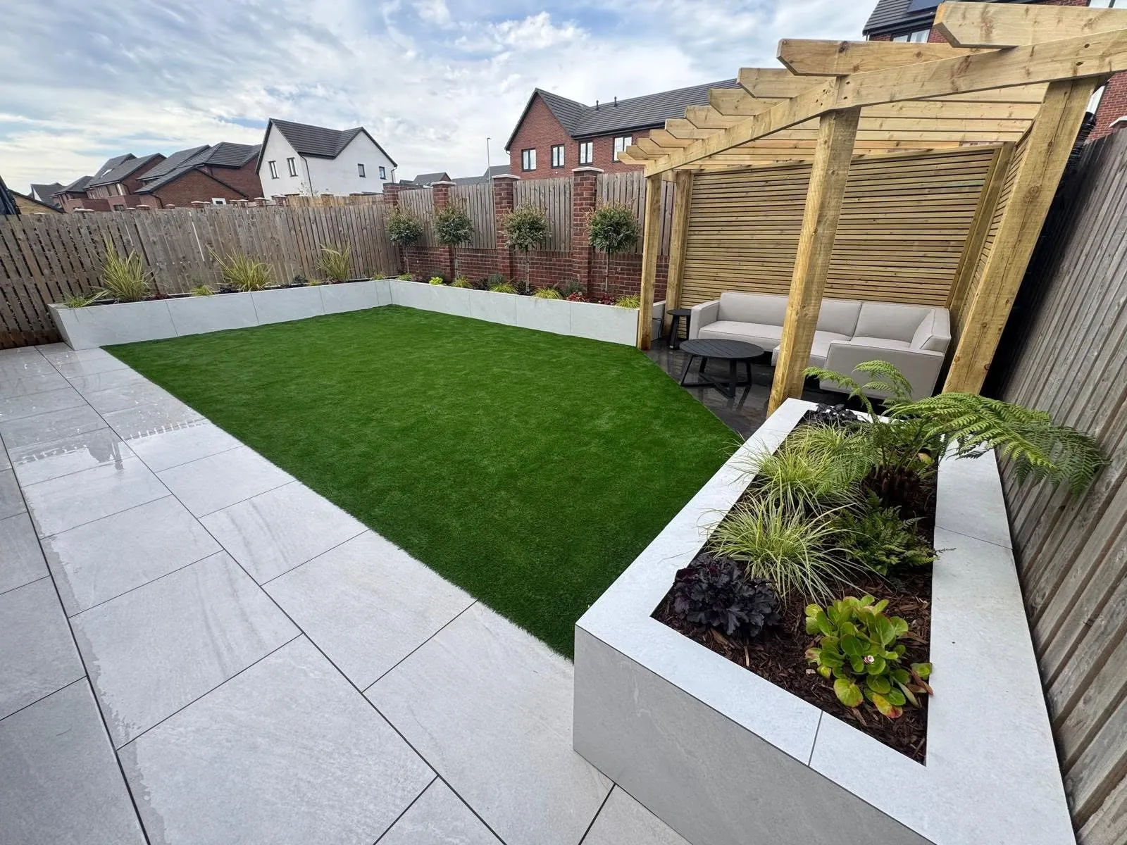New build garden transformation with lawn, porcelain paving, raised beds and timber pergola