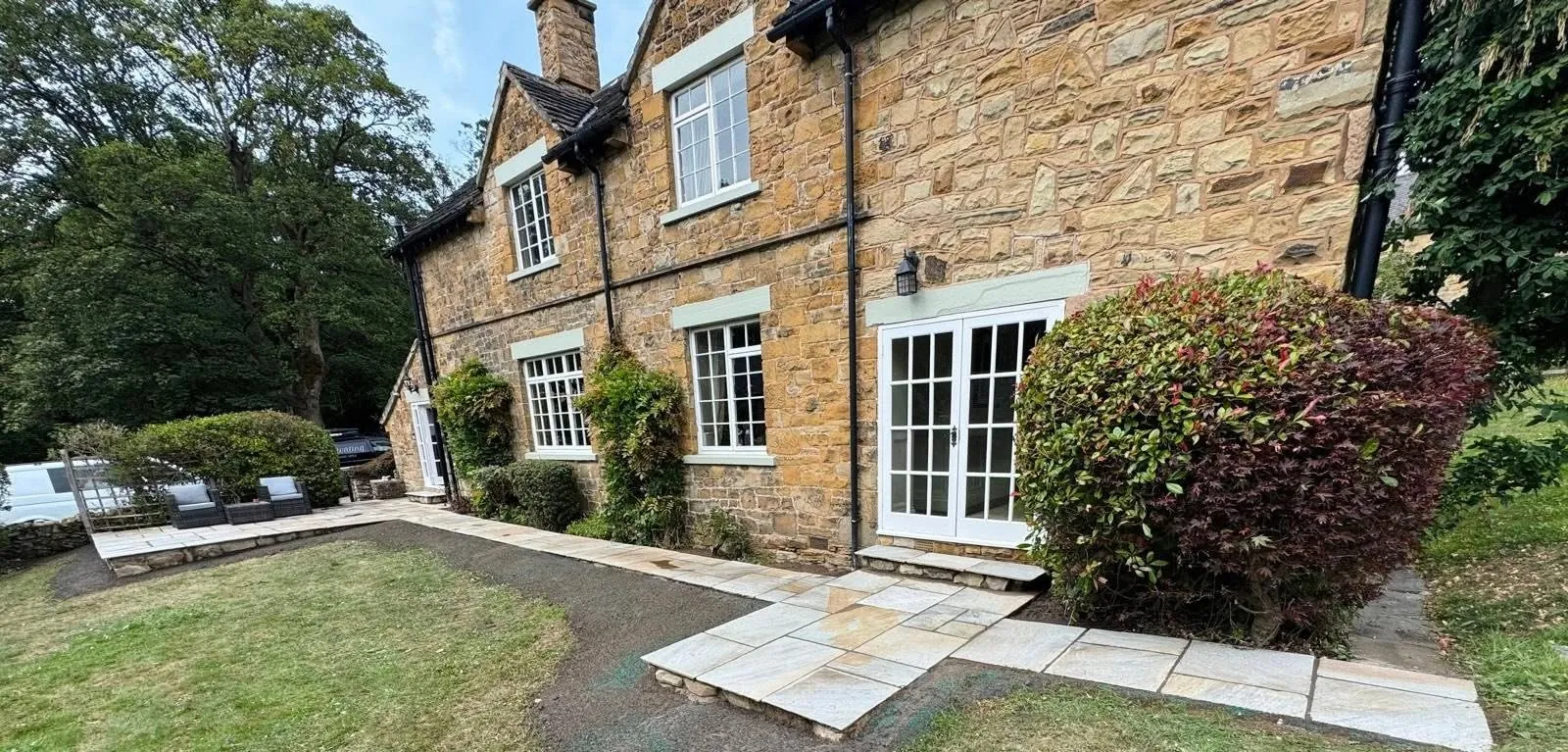 New patio paths and steps across a garden beside a stone house