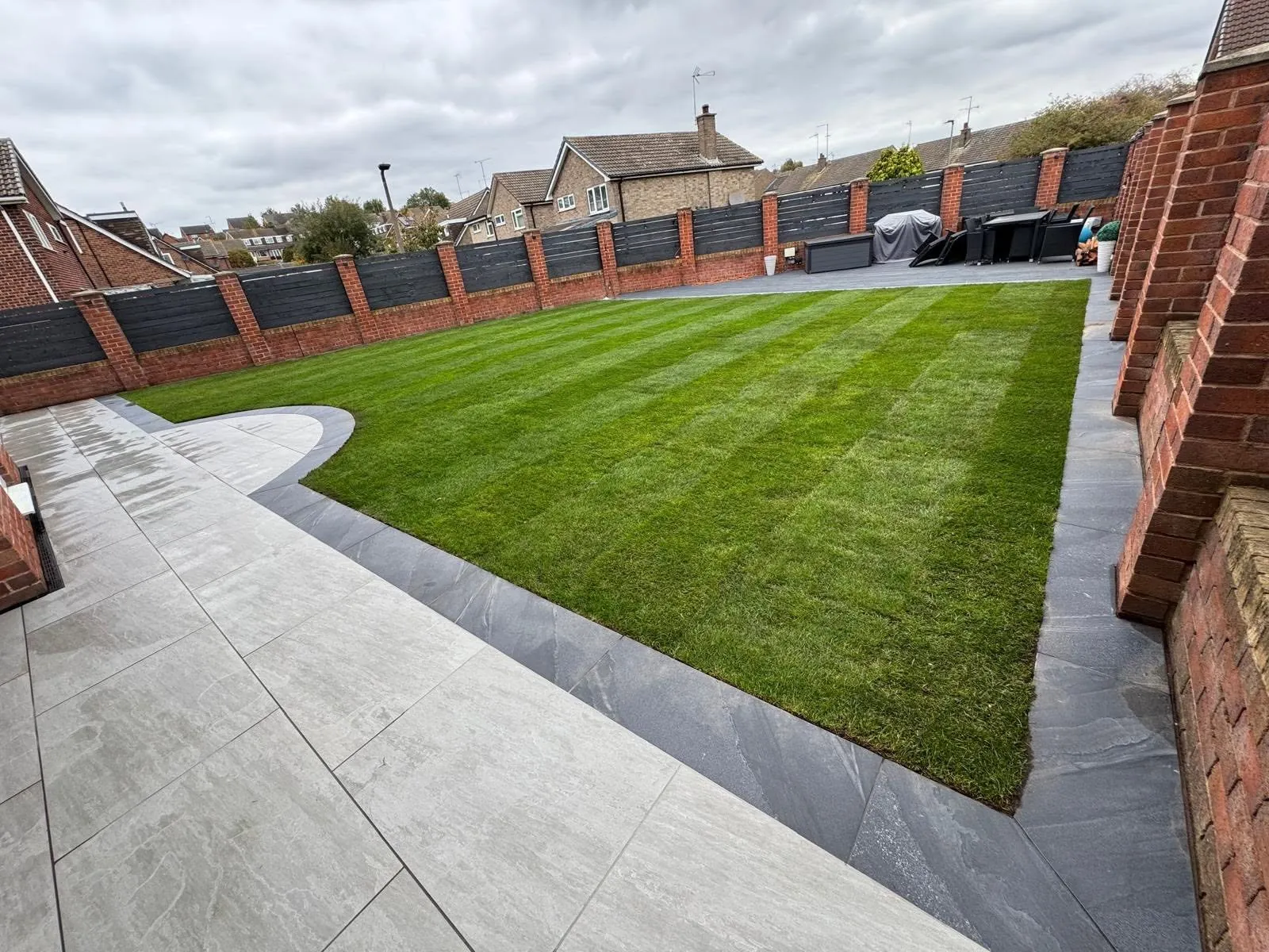 New natural turf lawn edged with pale paving