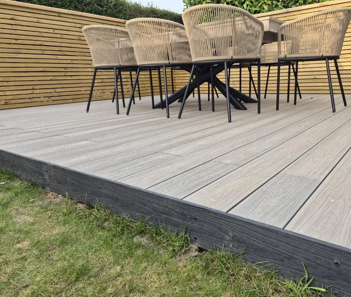 Close view of a grey composite deck edge with rattan dining chairs