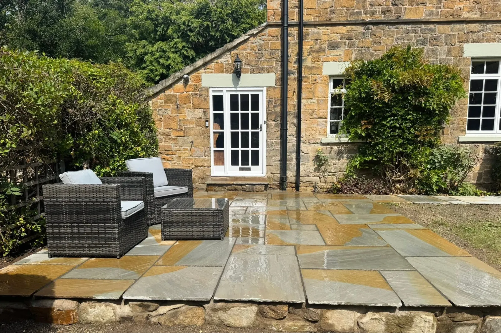 Natural stone flagstone patio with outdoor seating beside a stone house