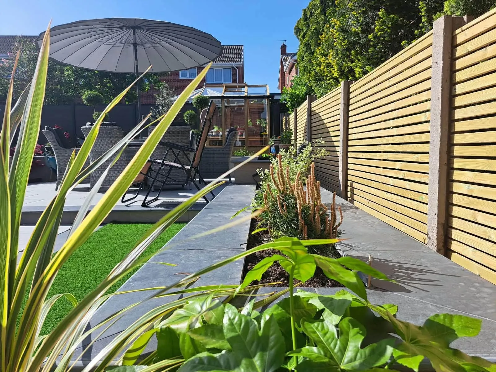 Long horizontal timber fence beside a garden path and planting