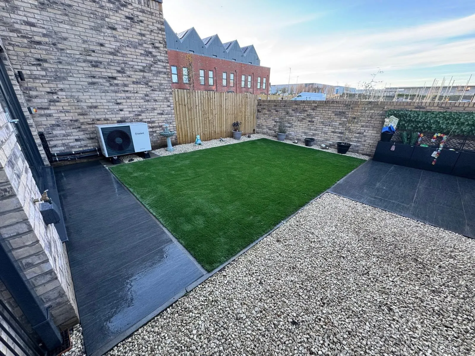 Artificial lawn bordered by dark paving and light gravel
