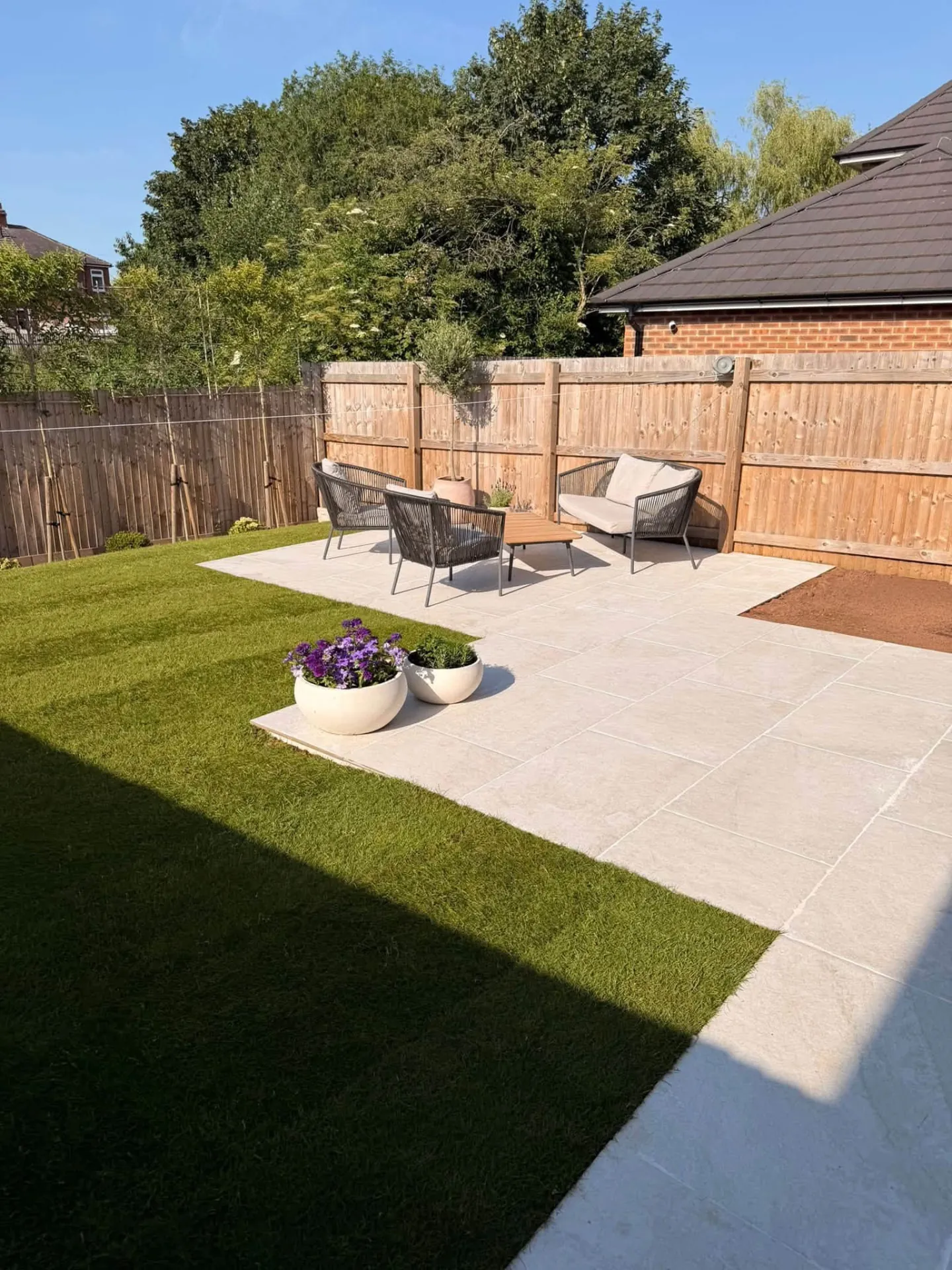 Sandstone patio beside a new lawn and timber fencing