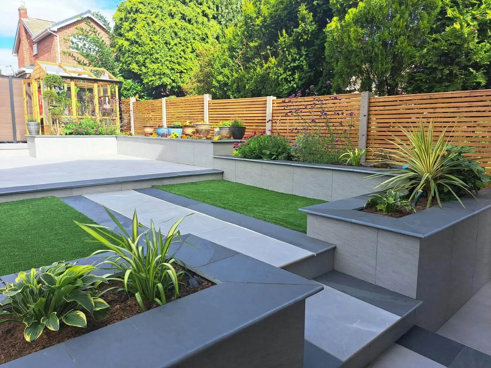 Grey raised planters and porcelain steps in a terraced garden