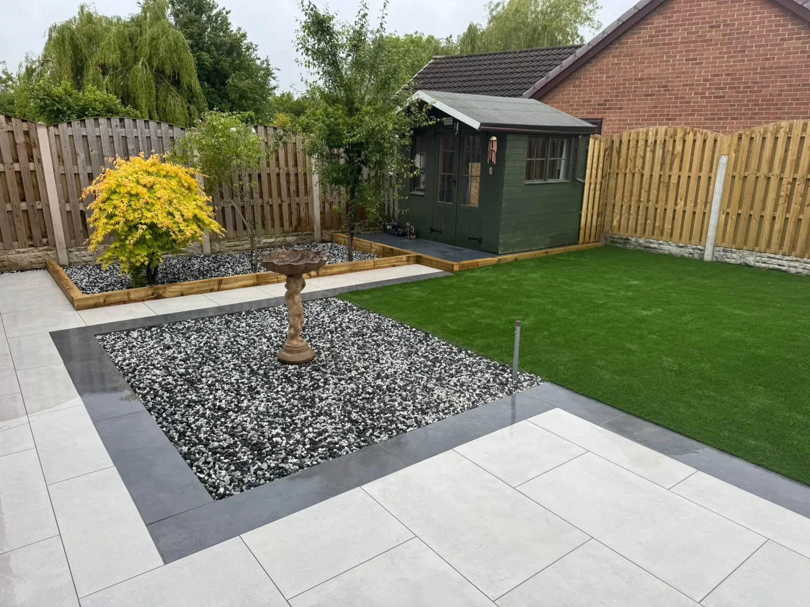 Landscaped back garden with lawn, gravel beds, paving and timber fencing
