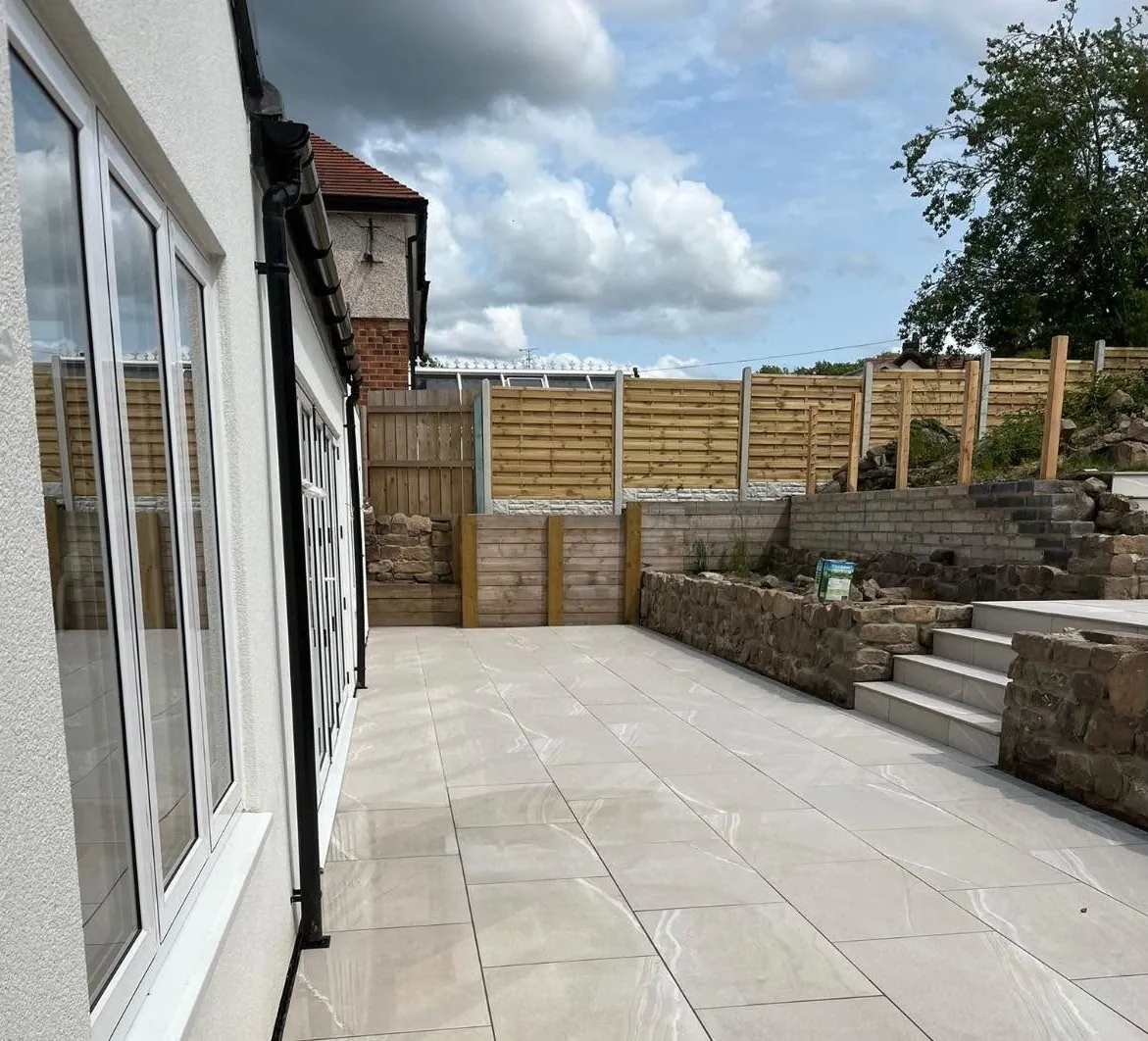 Porcelain patio and steps nearing completion behind a house