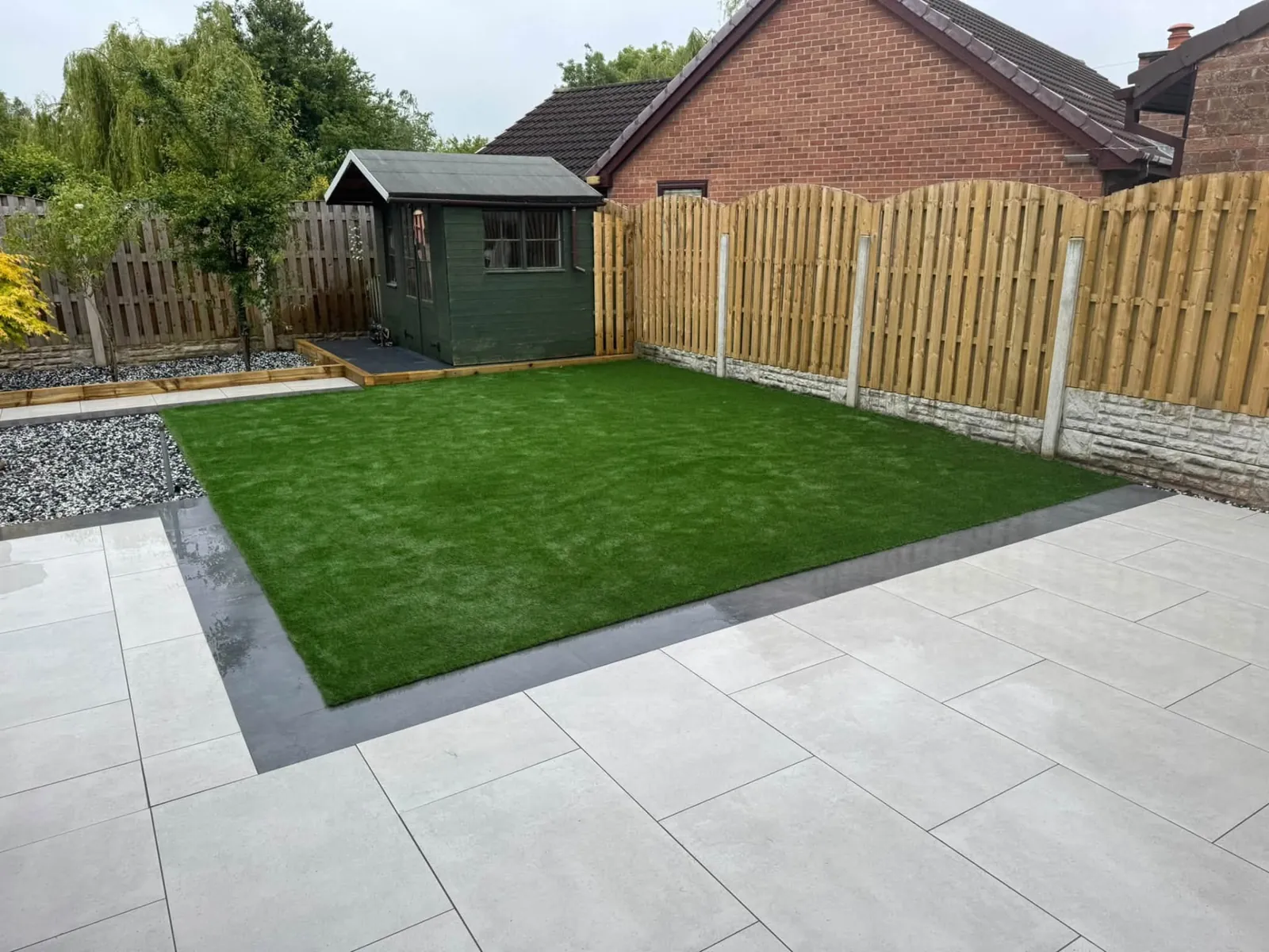 Large artificial grass lawn with pale paving, gravel and timber fencing