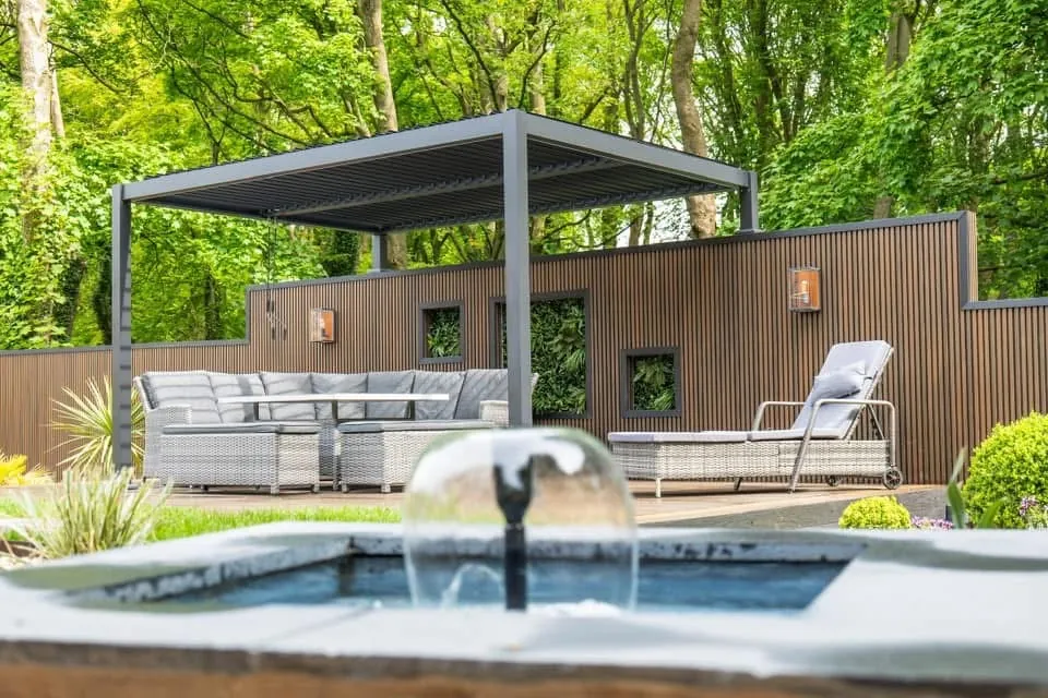 Bubbling water feature in front of a pergola seating area