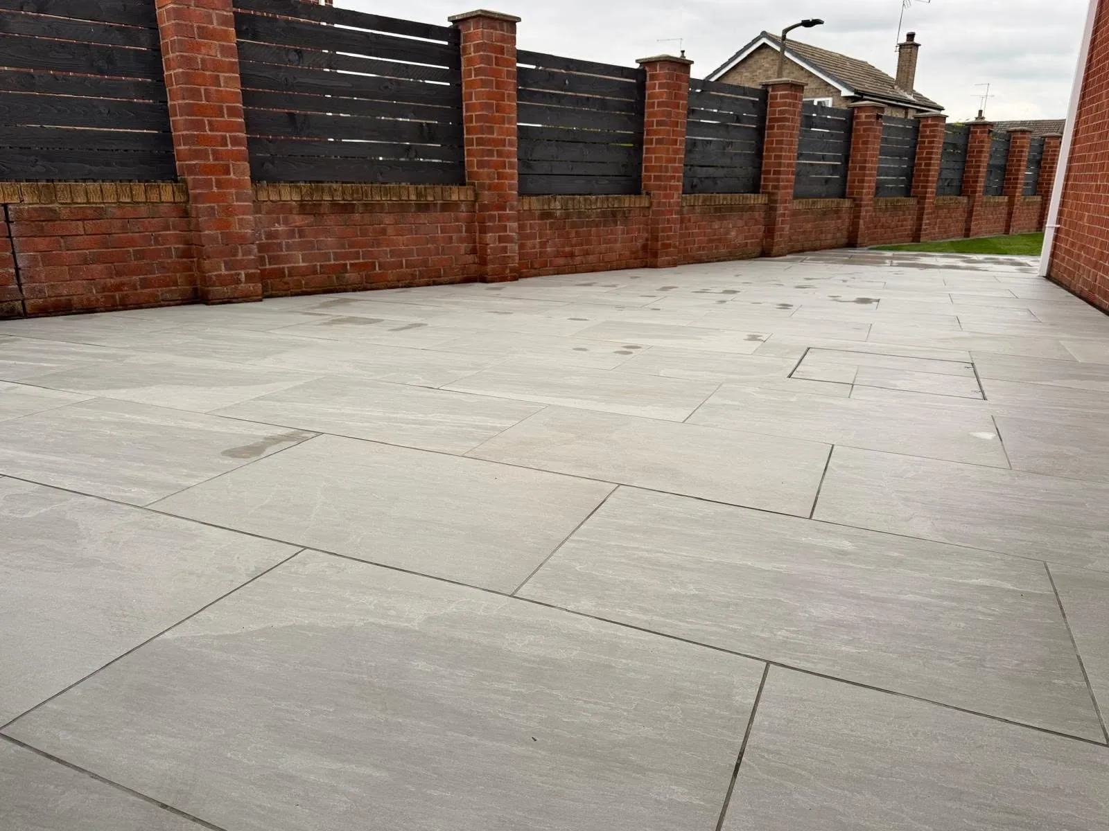 Large porcelain patio inside brick walls with dark slatted fence panels