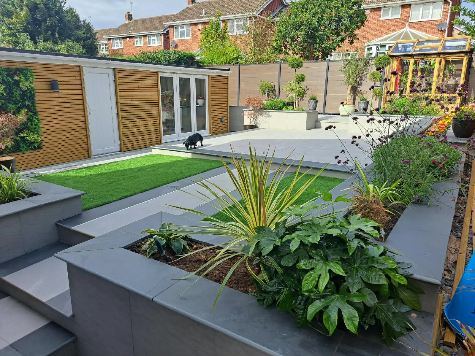 Garden transformation with porcelain steps, raised planters, artificial lawn and a garden room