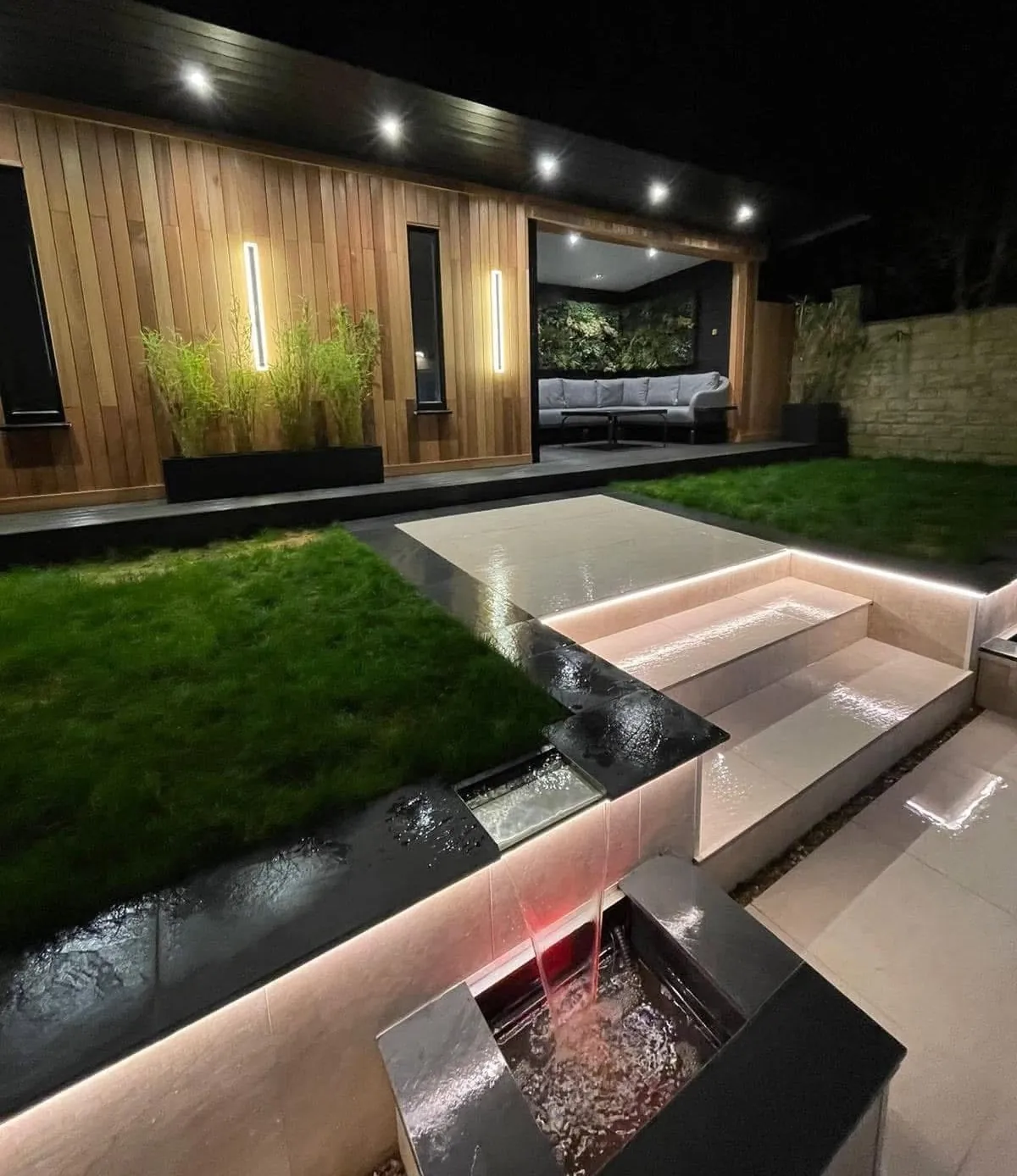 Lit water feature set into a modern garden at night