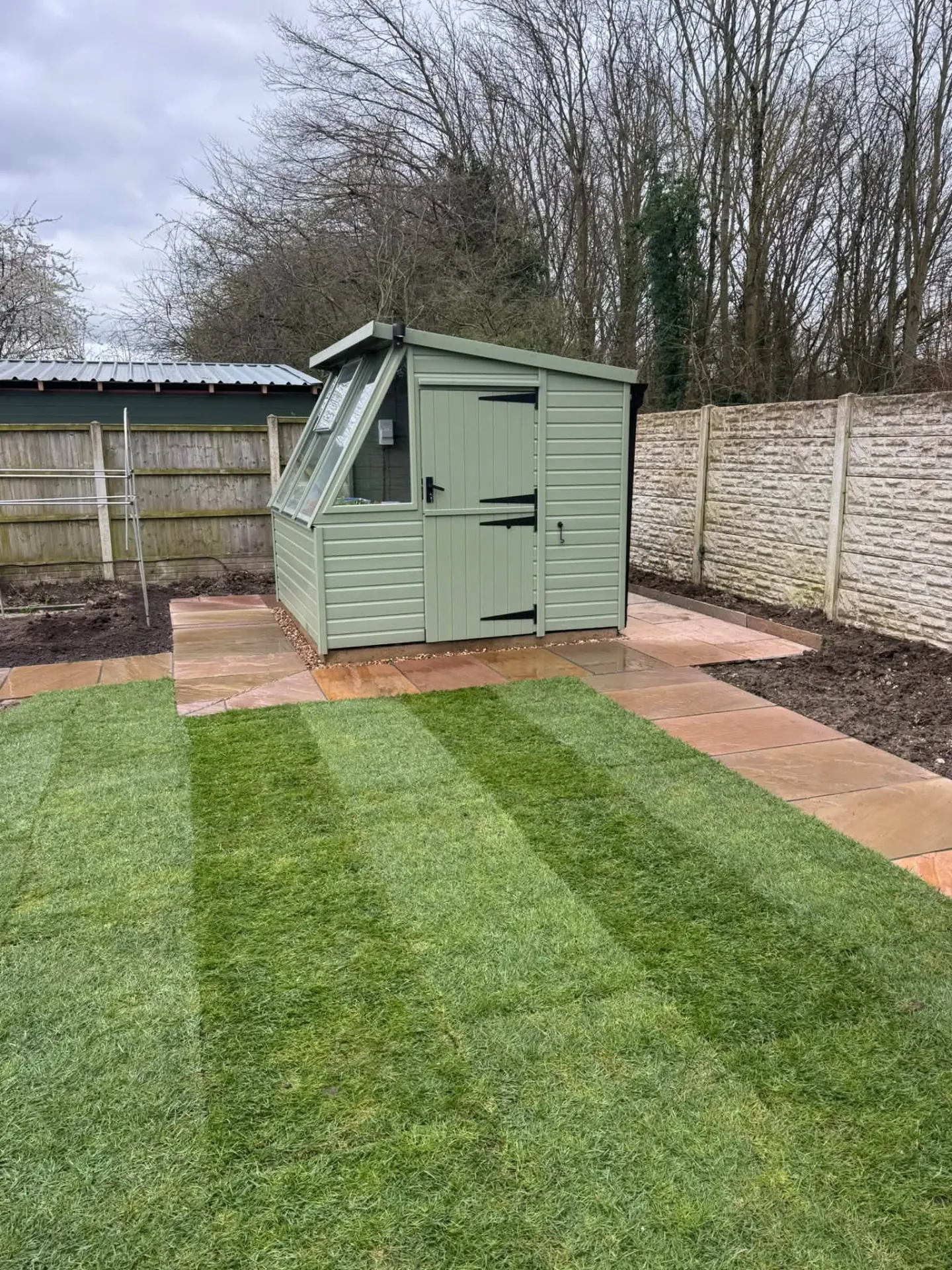 Freshly turfed lawn with paved path and planting beds