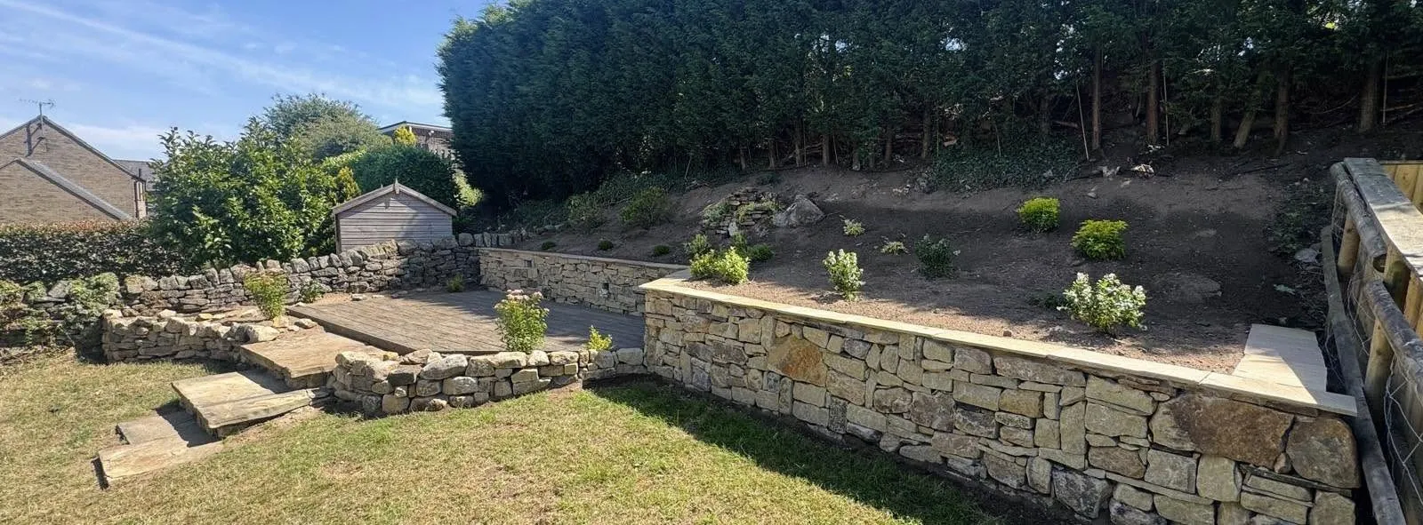 Panoramic view of a sloping garden terraced with dry stone walls and steps