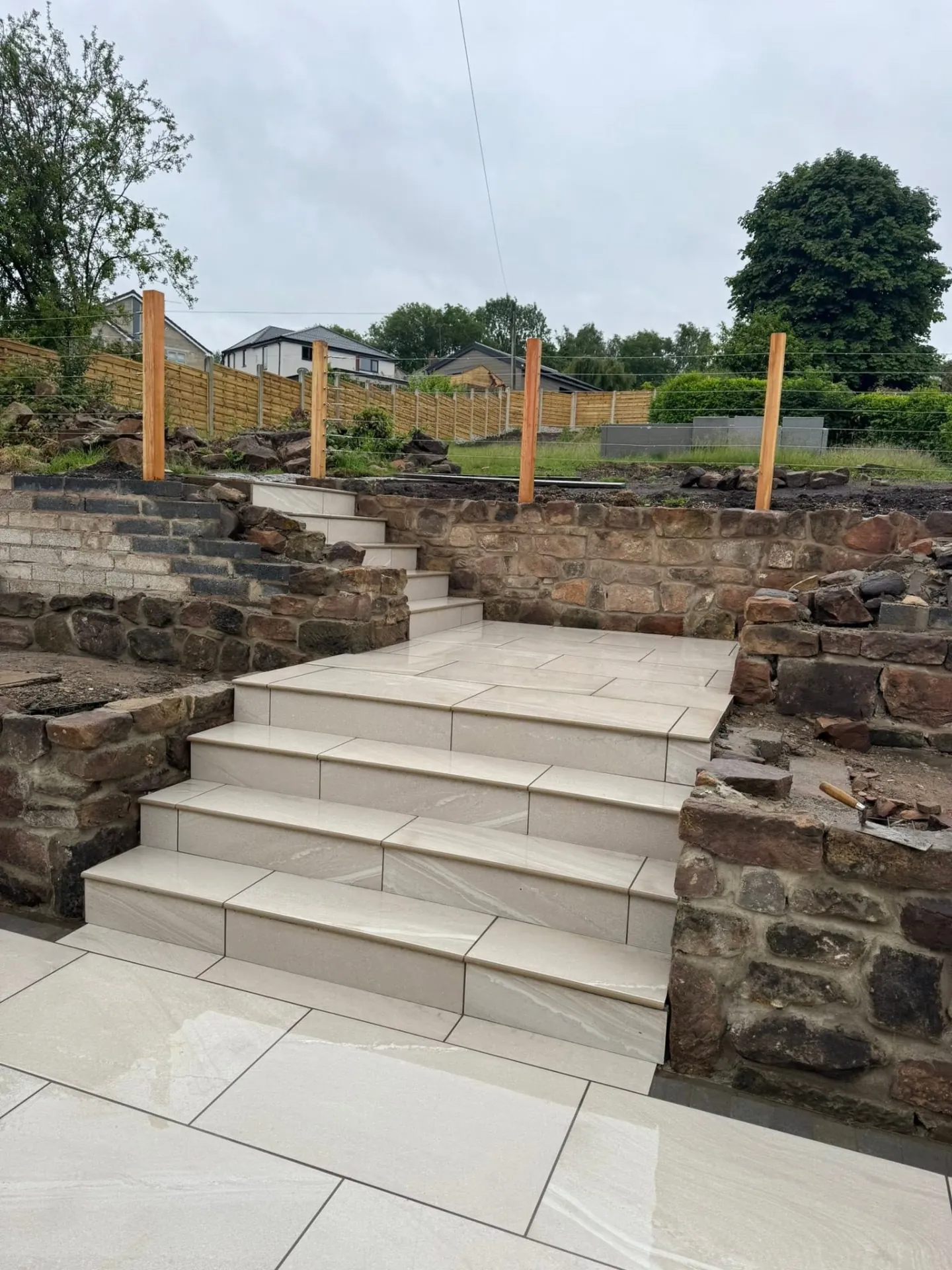 Porcelain steps being built into a sloping garden with stone walls