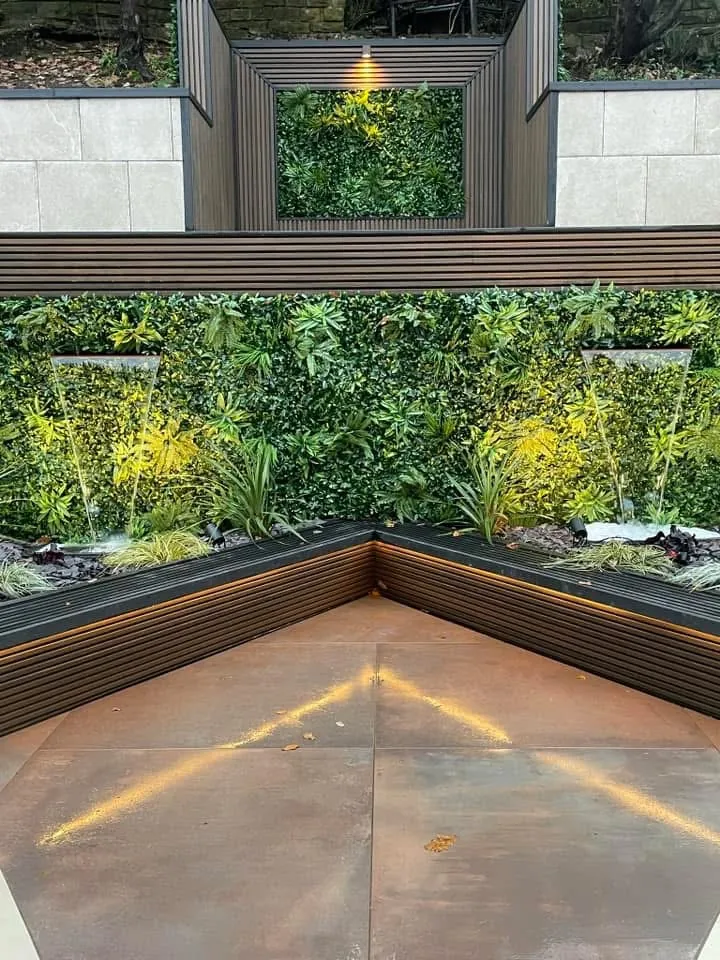 Living green wall with lit corten steel edging above porcelain paving