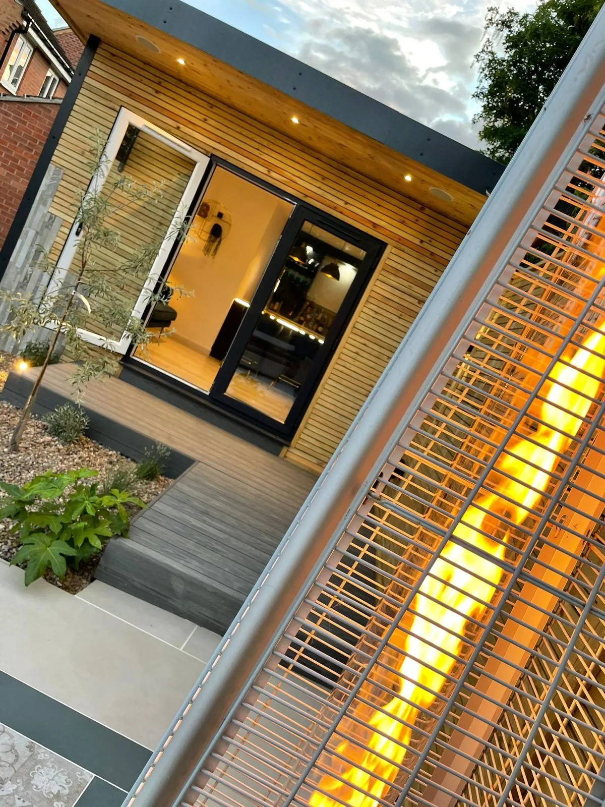 Garden room at dusk with glazed doors and lit slatted timber screen