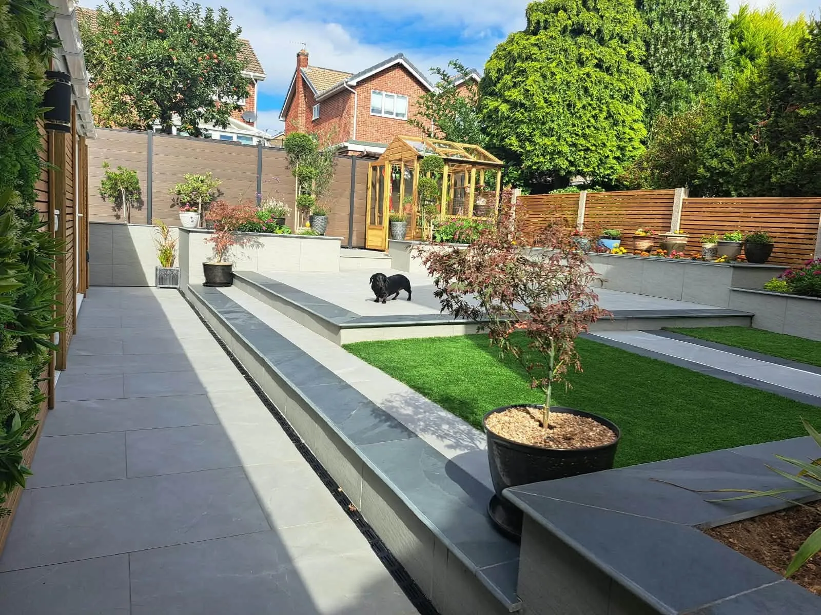 Large landscaped garden with raised paved terraces, lawn, planters and screening built by Captivating Landscapes